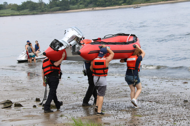 four members carrying a boat out to water