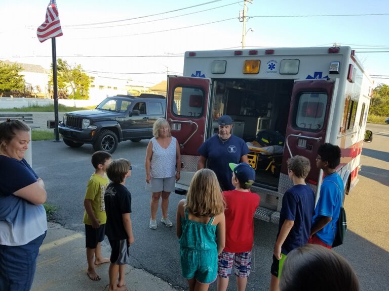 member talking to children behind ambulance